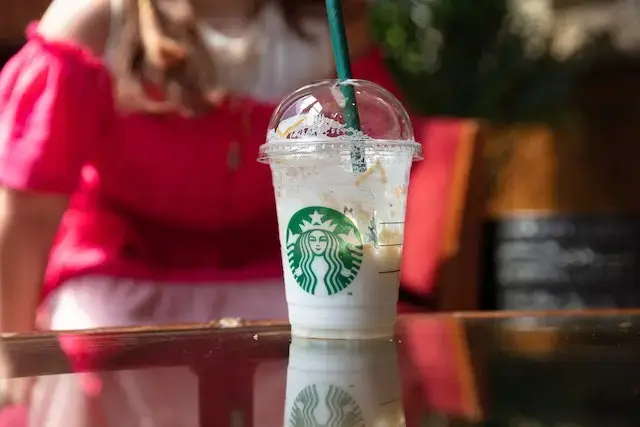 How to Add Extra Milk on Starbucks App? Half Empty Starbucks Cup Set on Table
