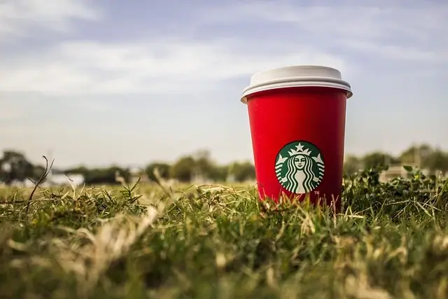 How to Add Peach Juice on Starbucks App? Grass and a red Starbucks cup 